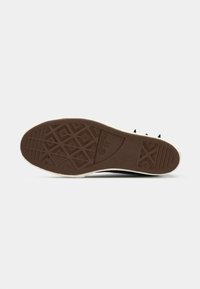 Súťažná podrážka so svetlohnedým gumovým vzorom obsahujúcim diamantové a hviezdne vzory a s embosovaným logom "Converse" v strede.