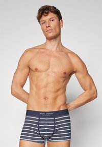 Marineblaue und weiße gestreifte Boxershorts mit elastischem Bund, gefertigt aus einem dehnbaren Stoff, der eine enganliegende Passform und eine glatte Textur bietet.