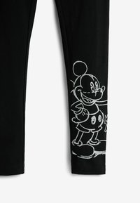 Fekete leggings, amelyek bal lábán egy mesefigura fehér körvonalas grafikája található. Puha, rugalmas anyagból készültek.