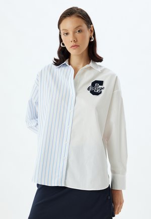 Hvid- og lyseblå stribet button-up skjorte med et broderet "College" logo på brystet, der har lange ærmer og en afslappet pasform.
