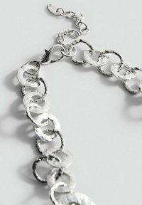 Braccialetto in metallo argentato a catena con anelli rotondi e texture, dotato di una chiusura sicura, che mette in risalto una finitura lucida e superfici irregolari.