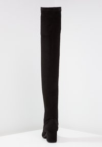 Botas negras hasta la rodilla hechas de suave ante, con una punta redondeada y un tacón cuadrado, presentando una textura lisa y detalles de costura mínimos.