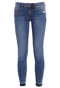 Jean skinny en denim bleu avec une taille mi-haute, présentant des signes d'usure légers, cinq poches, et une jambe fuselée avec des bords effilochés.