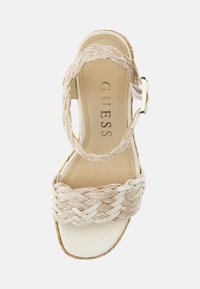 Beige platform sandal with braided straw upper, white leather straps, and gold-toned buckle. Smooth sole with woven edge detailing.