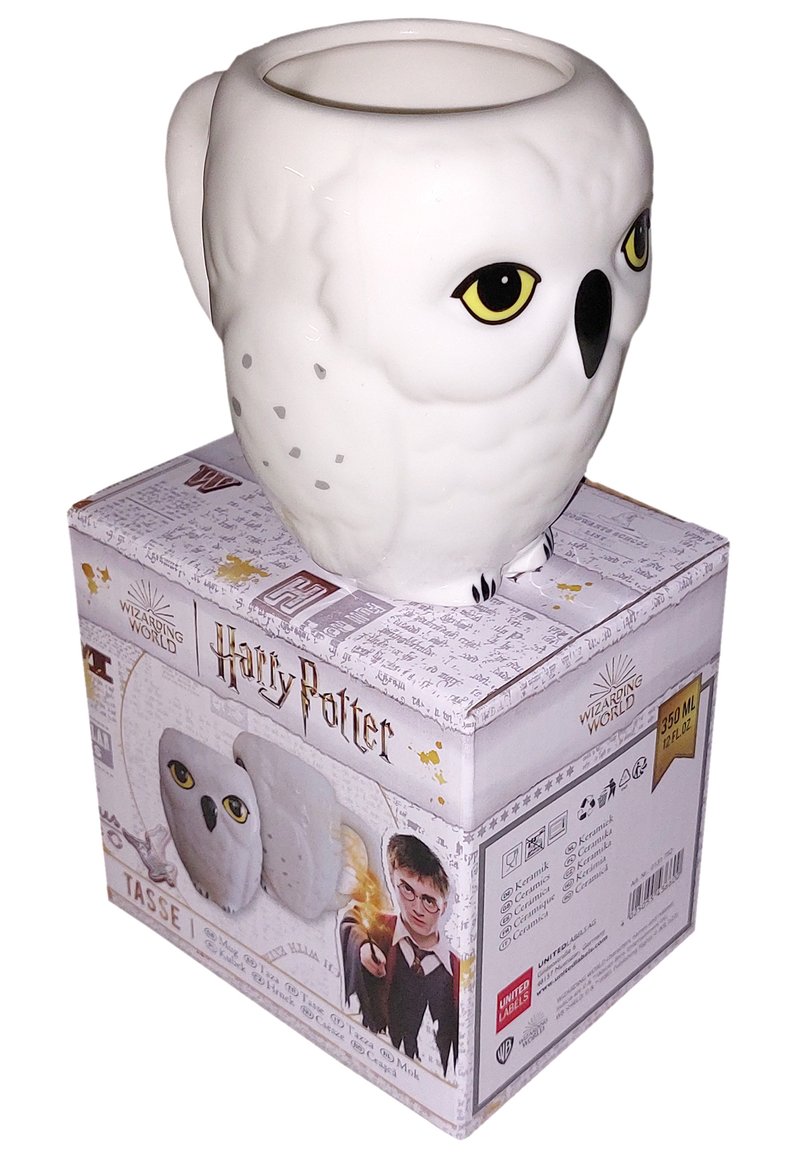 Tazza in ceramica bianca a forma di gufo, con grandi occhi gialli e un corpo texturizzato. La scatola è decorata con il marchio "Harry Potter" e illustrazioni.