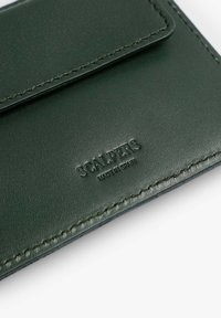 Portofel verde din piele cu margini cusute, având închidere cu clapă și branding embosat "SCALPERS MADE IN SPAIN". Textură netedă.