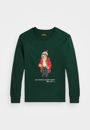 Donkergroen shirt met lange mouwen en een afbeelding van een beer die een rode jas, geruite broek en wintermuts draagt, met daaronder de tekst "Polo Bear by Ralph Lauren".