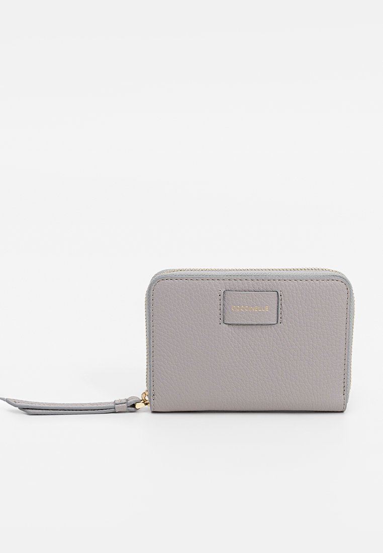 Jasnoszara, teksturowana skórzana portmonetka na zamek błyskawiczny z paskiem na nadgarstek i małym złotym logo wytłoczonym na środkowej części przodu.