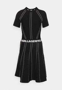 Black knit dress featuring short sleeves, a fitted bodice, flared skirt, vertical white dot patterns, and a waistband with "KARL LAGERFELD" text.