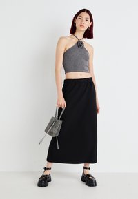 Γκρι ριπ λαιμόκοψη crop top με λουλουδάτο σχέδιο, μαύρη φούστα μέχρι τους αστραγάλους και μια μικρή τσάντα σε ασπρόμαυρο σχέδιο; χοντρές μαύρες πλατφόρμες.