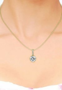 Collana in oro con pendente rotondo, dotato di una grande pietra centrale e piccole pietre disposte in una linea verticale sopra il pendente.