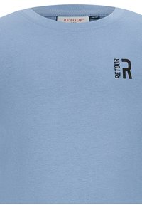 T-shirt in cotone di colore azzurro chiaro con collo a giro, caratterizzata da un logo nero "RETOUR" e un accento "R" nella zona sinistra del petto. Texture liscia.