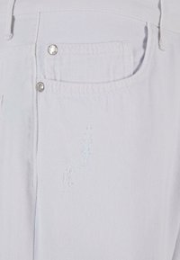 Pantaloni din denim alb cu o finisare texturată, având un buzunar pe spate, accesorii din metal și detalii ușor deteriorate pe țesătură.