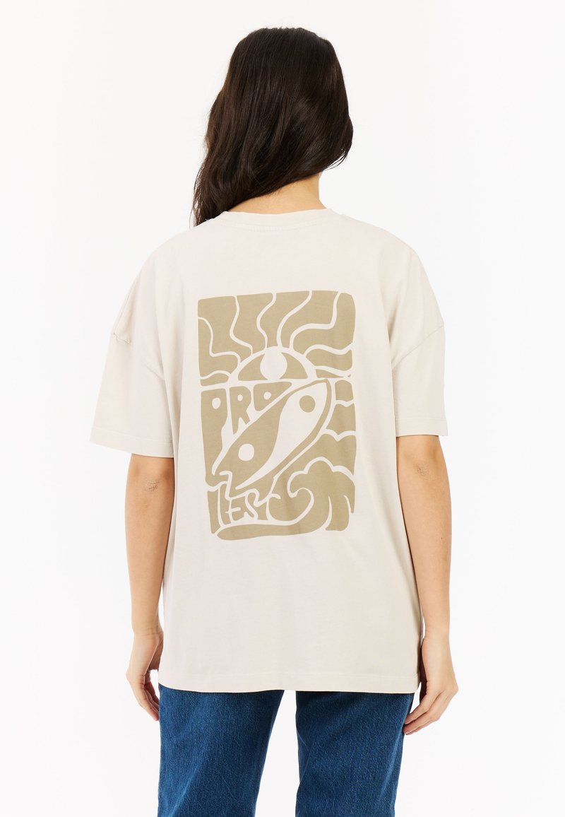 Beige katoenen t-shirt met een groot, abstract bruin ontwerp op de achterkant, met golvende lijnen en een vismotief. Korte mouwen en een relaxed fit.