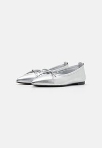 Ballerines métalliques argentées avec un bout pointu, un nœud décoratif et une semelle noire basse. Texture lisse avec un design élégant.