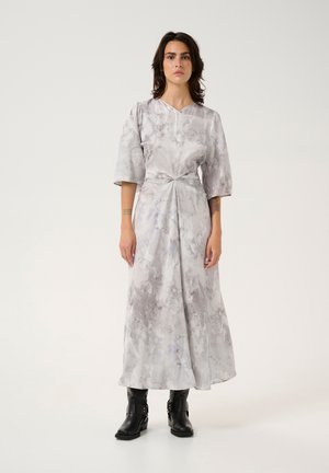 Gray marble-patterned maxi dress with short, wide sleeves and a knotted front detail. Worn with black ankle boots. Smooth fabric, elegant design.
