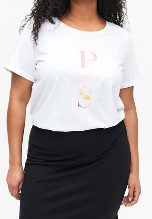 Femme portant un t-shirt blanc à manches courtes avec des lettres roses et dorées et une jupe noire, vue des épaules jusqu'aux hanches.