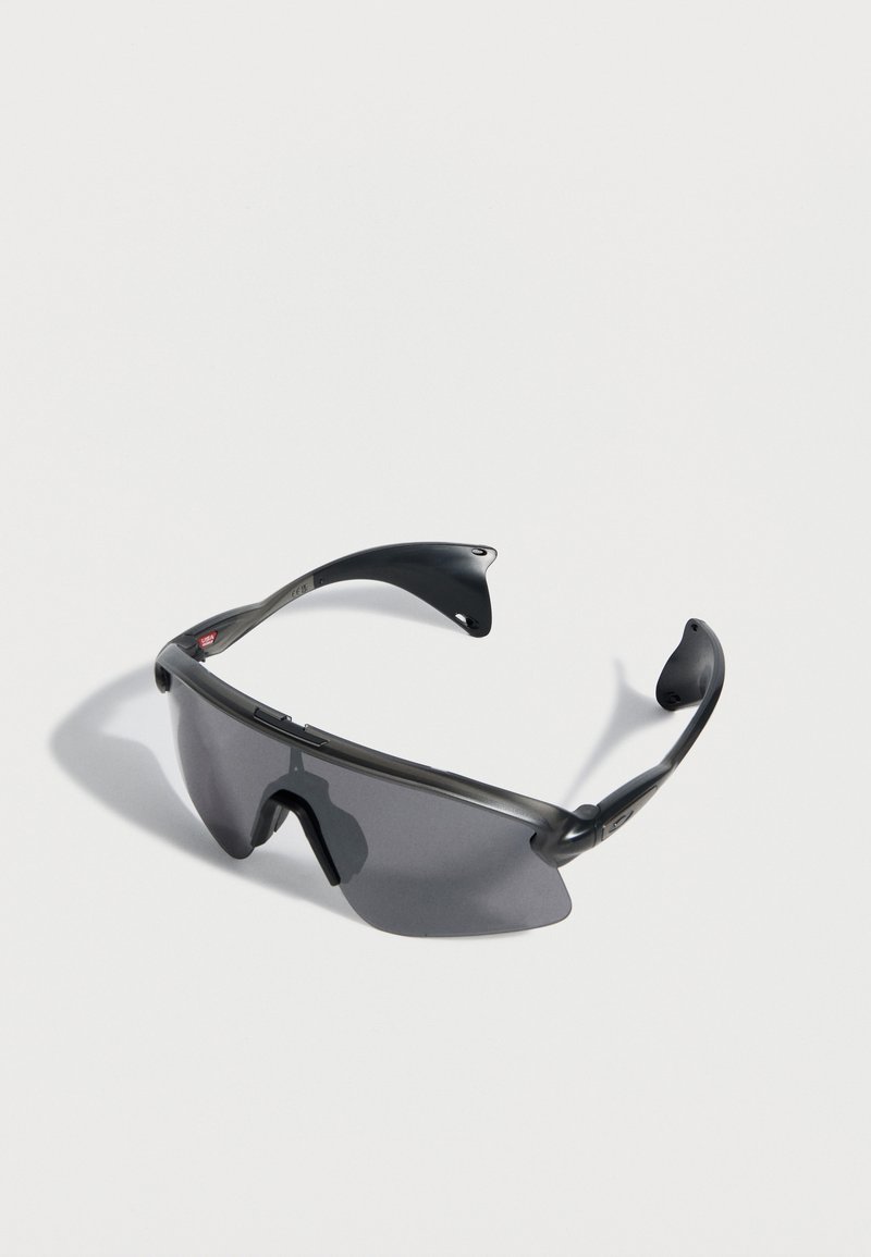 Μαύρα αθλητικά γυαλιά ηλίου με ένα ενιαίο σκοτεινό φακό και καμπυλωτούς βραχίονες σε λευκό φόντο.