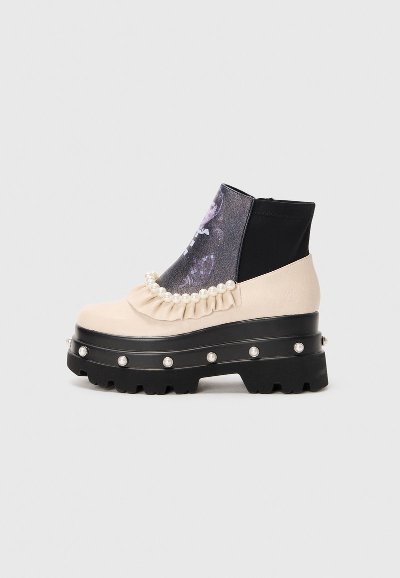 Chunky black platform boot with beige upper, pearl decorations along sole and cuff, ruffled trim, and printed dark panel on front.