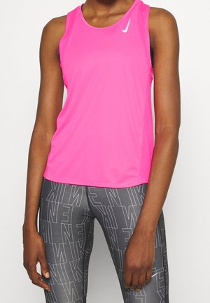 Vrouw draagt een felroze mouwloos sporttopje en grijze legging met herhaaldelijk wit "NIKE" tekstpatroon.