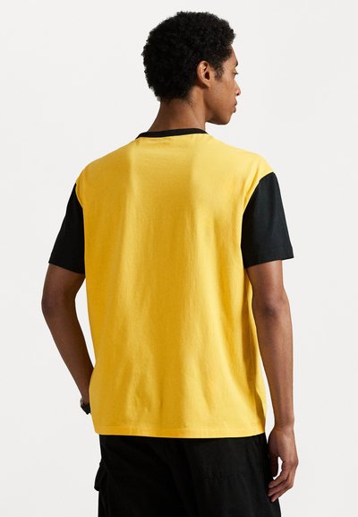 Gul og svart kortermet T-skjorte med rund hals, med et ensfarget blokkdesign og en myk bomullstekstur.