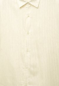 Kremowa koszula na guziki z pionowymi paskami, wyposażona w zakładany kołnierzyk i sześć guzik�ów z przodu, o gładkiej fakturze materiału.