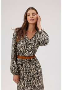 Sukienka w wzory z dekoltem w kształcie litery V i długimi bufiastymi rękawami. Beżowo-czarny abstrakcyjny wzór, w talii zaciśnięta brązowym pasem, miękka tekstura.