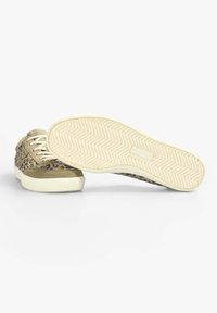 Leopridierte Sneakers mit Obermaterial aus beigefarbenem Wildleder und Stoff, cremefarbener Gummisohle mit Chevron-Laufsohle. Schnürsenkel und weiche Textur sichtbar.
