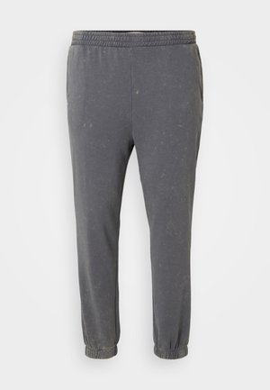 Graue, weiche Stoff-Jogginghosen mit elastischem Bund. Schmal zulaufende Beine und gesäumte Säume, die eine subtile, abgenutzte Textur aufweisen.