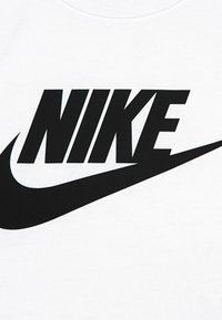 Λευκό βαμβακερό T-shirt με μεγάλο μαύρο λογότυπο Nike και το χαρακτηριστικό σχέδιο swoosh. Η υφή φαίνεται λεία και η εκτύπωση έντο νη.