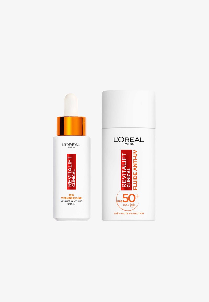 Sérum Revitalift Clinical avec un capuchon orange et pipette à côté du Fluide Anti-UV Revitalift Clinical. Les deux ont des contenants blancs avec du texte rouge.