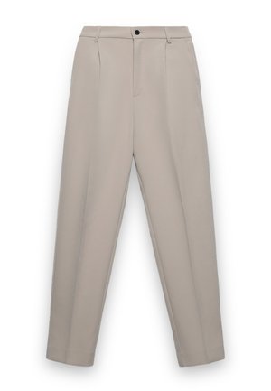 Beige maßgeschneiderte Hose mit Gürtelschlaufen, vorderem Knopf, Reißverschluss, Seitentaschen und gebügelten Biesen an jedem Bein.