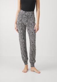 Pantalons de jogging à motifs noir et blanc avec une taille élastique et des chevilles élastiquées, fabriqués en tissu doux.