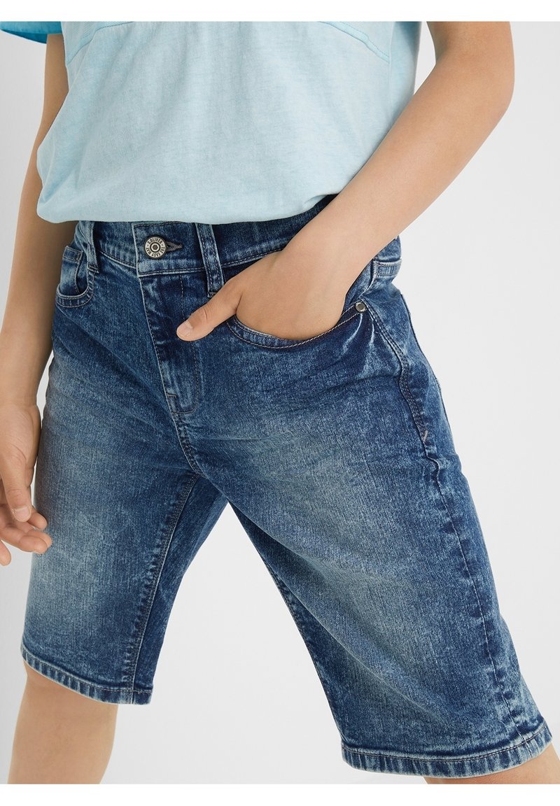Shorts en denim de couleur bleu délavé avec une coupe décontractée, cinq poches et une taille avec un bouton en métal et une fermeture éclair.