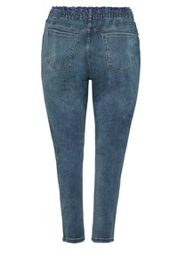 Blå denimjoggers med elastisk midja, smalnande ben och två bakfickor. Texturen är slät med en blekt finish.