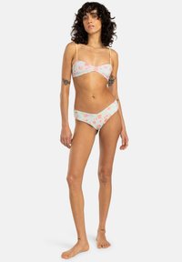 Blomstrete bikini-sett med lys blå bakgrunn og rosa og oransje blomster. Toppen har tynne stropper, og bunnene har lavt liv.