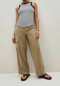 Stribet sort og hvid ærmeløs top parret med khaki cargo bukser med sidelommer. Bæret med sorte flip-flops.
