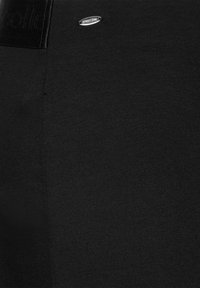 Leggings neri realizzati in tessuto morbido. Presentano una vita testurizzata con dettagli del logo. Texture liscia e design aderente.