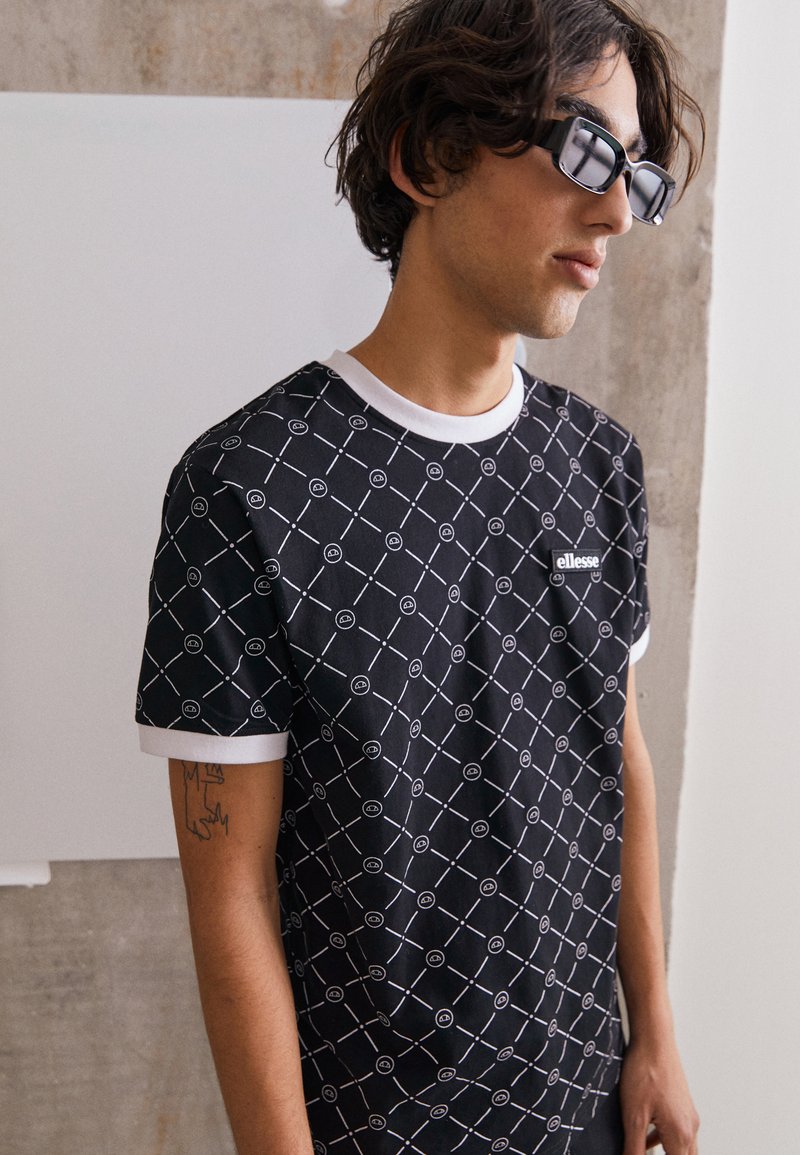Black short-sleeve t-shirt with white geometric pattern and trim. Features small logo patch on chest; made of smooth fabric. Casual fit.
