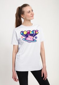 Hvid t-shirt med korte ærmer, der har et farverigt grafisk design med ordet "COSMIC" og en tegneserie-bjørn omgivet af planeter og stjerner.
