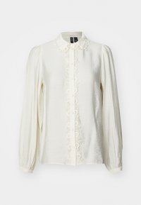 Blusa de manga larga en color crema con un placket de botones adornado con encaje, hombros plisados y una tela suave y texturizada. Los botones son redondos y están uniformemente espaciados.