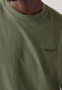 Camiseta de algodón color verde oliva con cuello redondo y un logo de Levi's texturizado bordado en el mismo color en el pecho.