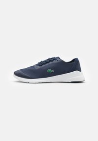 Navy sneaker with a textured mesh upper, smooth rubber accents, white sole, and tonal laces. Features a small green logo detail.