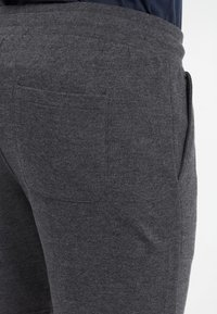 Dark gray joggers made of soft fabric, featuring a thick elastic waistband and a back pocket with a smooth finish.