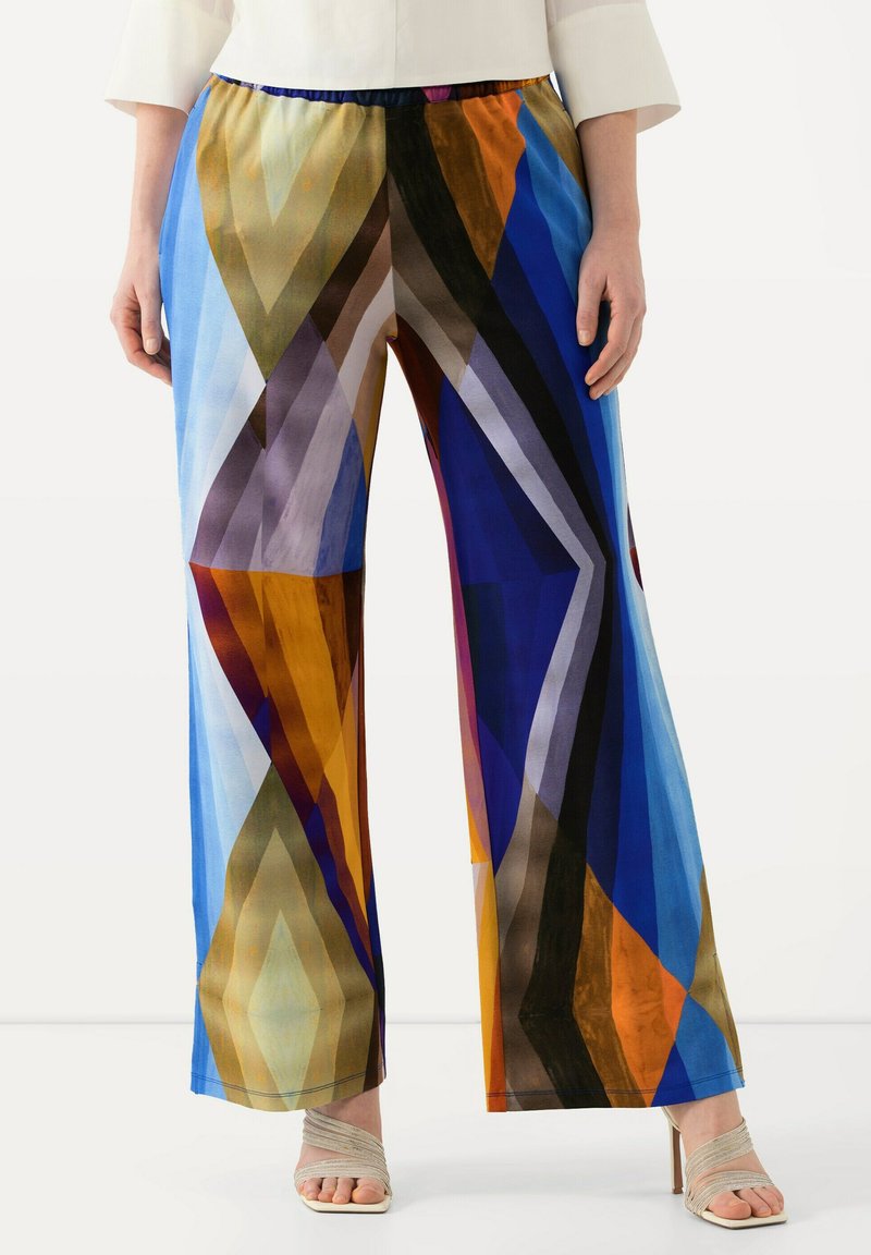 Kleurige wijde broek met een geometrisch patroon in tinten blauw, oranje, bruin en paars. Elastische tailleband en een gladde stof.