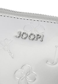 Sølv faux læder pouches med præget blomster mønstre og et fremtrædende sølv "JOOP!" logo. Tekstureret lynlåsdetalje.