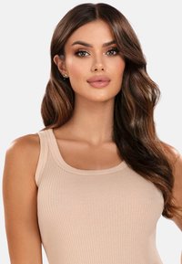 Beżowy prążkowany top bez rękawów z okrągłym dekoltem i szerokimi ramiączkami. Wykonany z miękkiego materiału o lekko teksturowanej powierzchni.