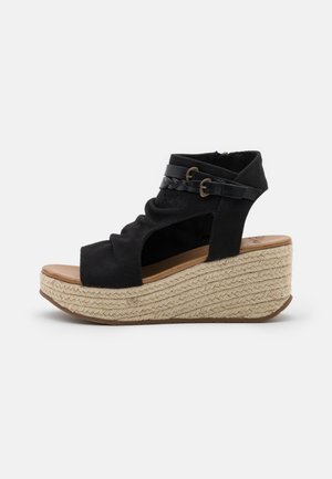 Sort åben tå kile-sandal med vævet jute-platformsål og dobbelt spænde rundt om anklen.