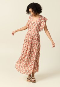 Maxiklänning med volangärmar i ett geometriskt mönster med rött, krämfärgat och svart. Tyg är lätt och med elastisk midjeresår.