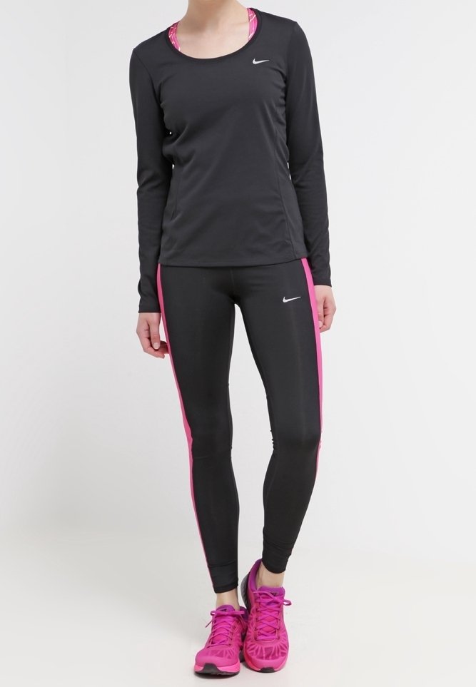 Musta pitkähihainen urheiluvaate yhdistettynä mustiin legginsseihin, joissa on vaaleanpunaiset sivuviivat, sekä kirkkaat vaaleanpunaiset urheilukengät. Nike-logot näkyvissä.